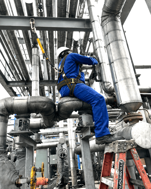 Engineer performing maintenance on industrial piping with safety harness